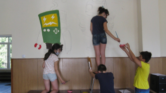Учител и малките му художници рисуват по училищни стени